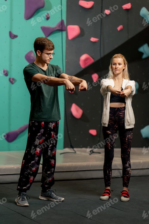 Preview: young girl at a climbing wall with a trainer doing a warm-up before rock climbing training
