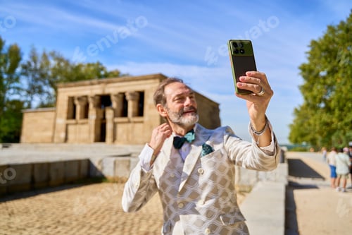 Preview: Man taking a selfie with smartphone near ancient stone temple outdoors
