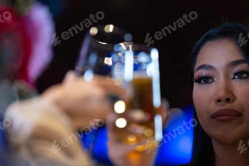 Preview: Close-up of two female friends toasting and clinking glasses of wine and beer
