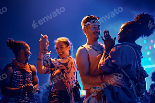 Preview: Group of happy friends having fun and dancing at summer music festival at night.