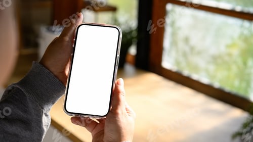 Preview: Person holding empty screen smartphone over kitchen counter in natural morning light