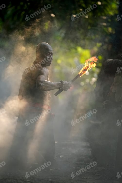 Preview: Man holding torch in misty woods during a ceremonial gathering at dusk