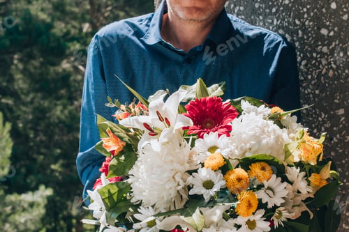Preview: A middle-aged man in a blue shirt with bright bouquet of fresh multicolored mixed flowers. Close up.