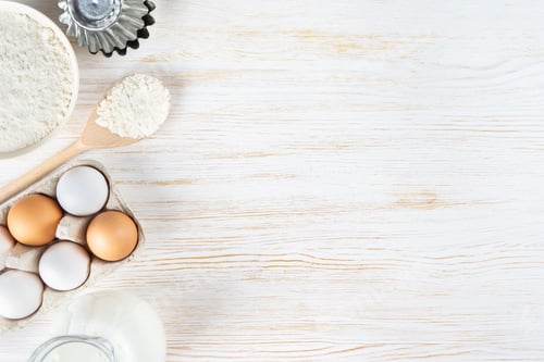 Preview: Baking Ingredients Flour, Eggs, Milk, Bakeware on White Wooden Background with Copy Space