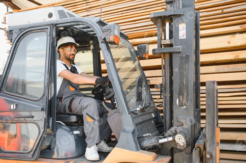 Preview: Warehouse worker driving forklift in lumber storage area