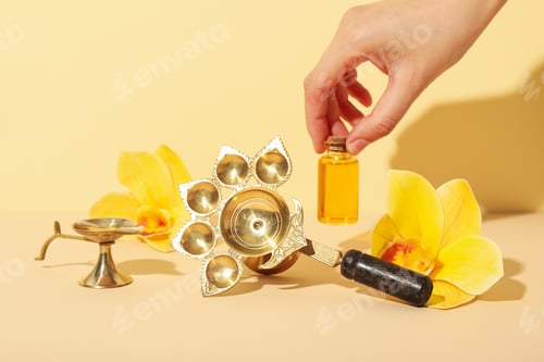 Preview: Copper oriental utensils, flowers and bottle of oil in hand on beige background