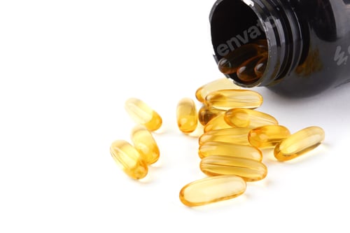 Preview: Amber Pills Spilling from Bottle on White Surface