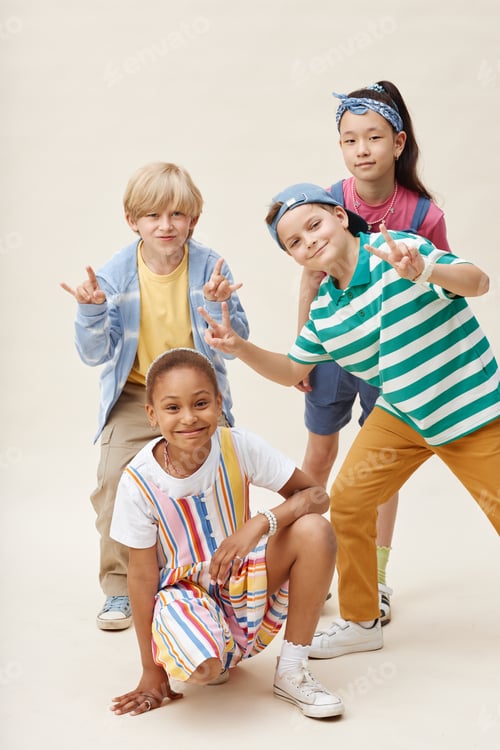 Preview: Multiethnic Group of Four Smiling Kids Showing Funny Gestures while Posing in Studio