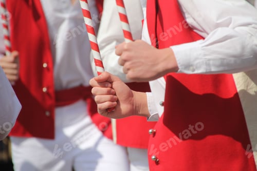 Preview: People in traditional red and white costumes holding striped sticks
