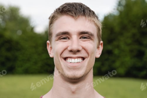 Preview: Young happy man smiling and looking at camera outdoor at city park - Focus on face
