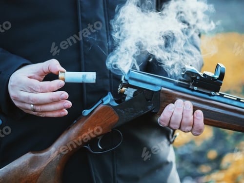 Preview: Sports shooting. Hunter reloading cartridge.Smoke from trunks of smooth-bore hunting rifle firing.