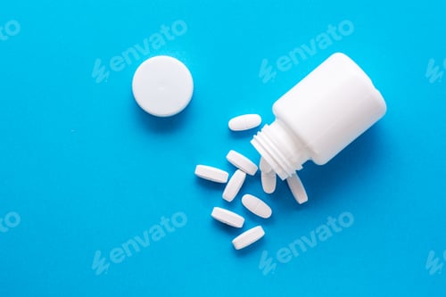 Preview: White large pills fall out of the bottle and scattered on a blue background.