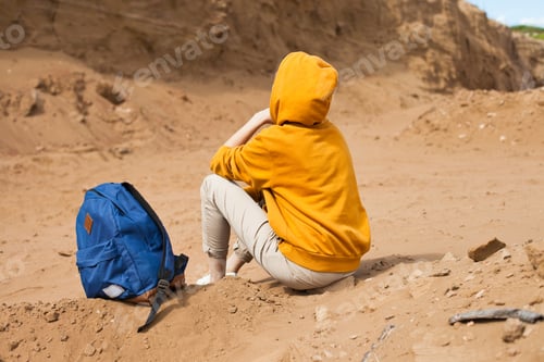 Preview: A young woman in yellow hoodie with a blue backpack hiking, female backpacker, backpacking, tourist