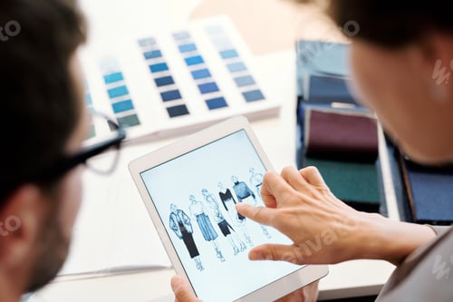 Preview: Young female fashion designer pointing at one of model sketches