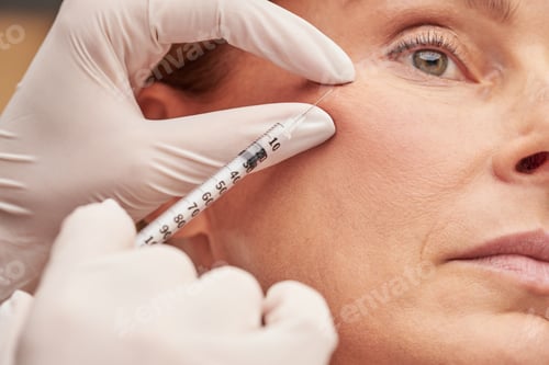 Preview: Anti aging cosmetology. Close up of a caucasian mature woman getting cosmetic injection in her cheek