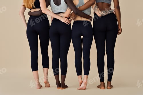 Preview: Young diverse women wearing sportswear standing back on beige background.