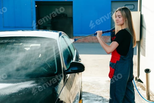 Preview: Woman Worker in Uniform Washing Car with High Pressure Gun with Hose at Car Wash Station