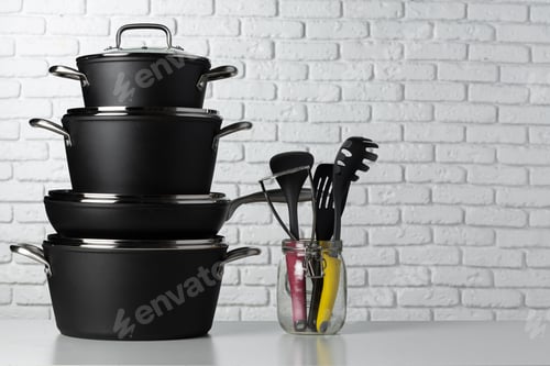 Preview: Black kitchenware on table against white brick wall