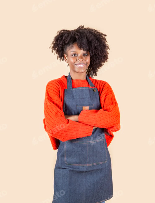 Preview: pretty Hispanic woman with apron, working woman with crossed arms, beige background