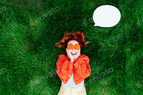 Preview: Wow. Emotional surprised, shocked redhead woman with red orange gerbera Flower glasses on grass