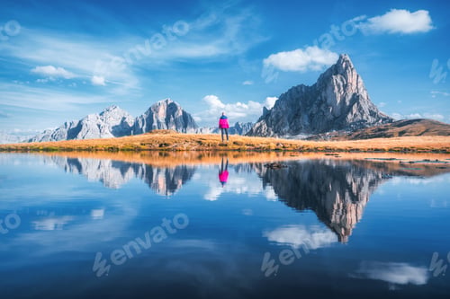 Preview: Woman and mountains reflected in lake at sunny day in autumn