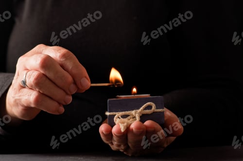 Preview: Hands of a woman lighting a candle with a match