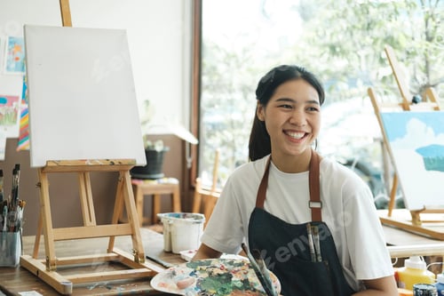 Preview: Young Asian female artist in art studio look at camera and smiling.