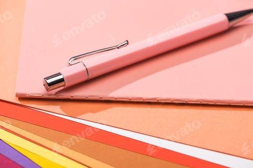 Preview: selective focus of pen and notebook on bright and colorful papers