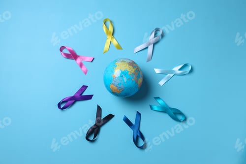 Preview: Earth globe surrounded by colorful awareness ribbons on blue background. World cancer day concept.