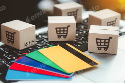 Preview: Shopping online. Credit card and cardboard box with a shopping cart logo on laptop keyboard.
