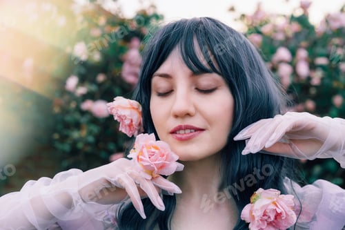 Preview: Fairy tale woman portrait. Young beautiful woman Fairy holds pink flower rose on blooming bush