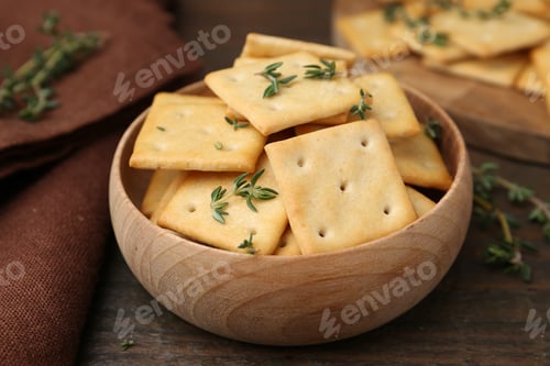 Preview: Tasty salty crackers with thyme on wooden table, closeup