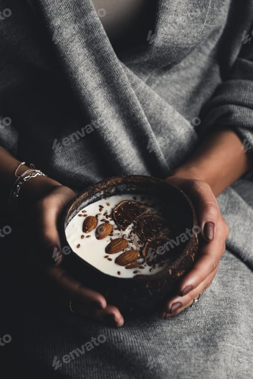 Preview: Healthy breakfast. Сoconut bowl in the hands of a girl with yogurt and figs. Healthy food. Veganism.