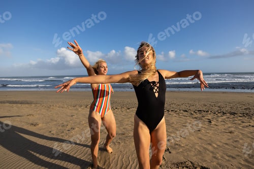 Preview: Two women having fun dancing at sunset on the beach