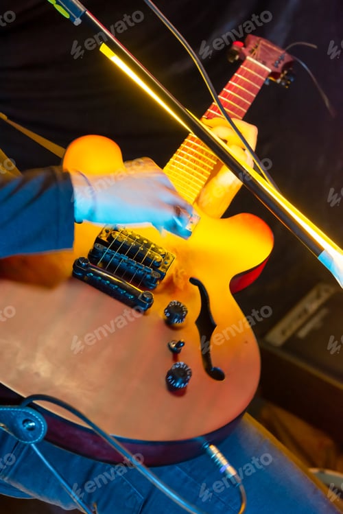 Preview: the musician plays the guitar at the concert of a rock band in the club.