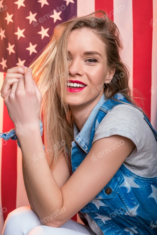 Preview: young smiling caucasian woman posing in front of USA flag, Independence Day of America