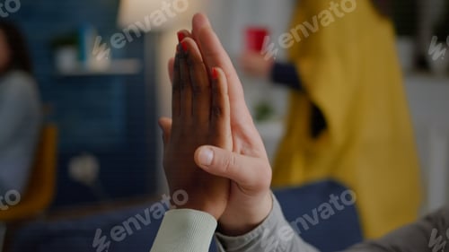 Preview: Closeup of multiethnic friends giving high five during celebration party