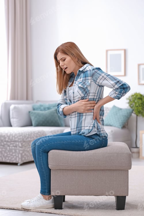 Preview: Young woman suffering from back pain at home