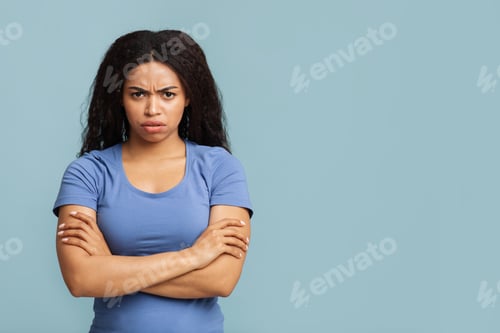 Preview: Grumpy woman. Portrait of serious black lady standing with crossed arms, posing over blue background