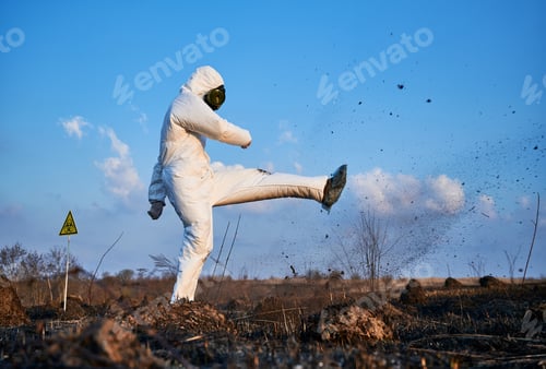 Preview: Lab worker in a protective costume working in scorched field