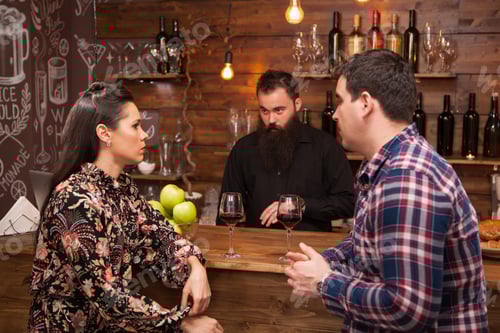Preview: Couple talking to bartender behind bar counter in a cafe.