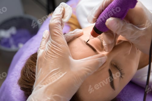 Preview: Beauty master performs permanent eyebrow makeup in a beauty salon, microblading, close-up
