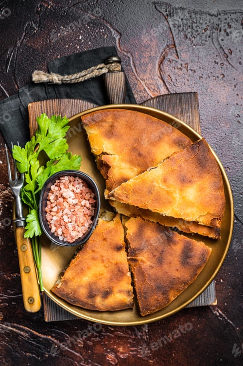 Preview: Traditional Ossetian pie sliced on a plate. Dark background. Top view