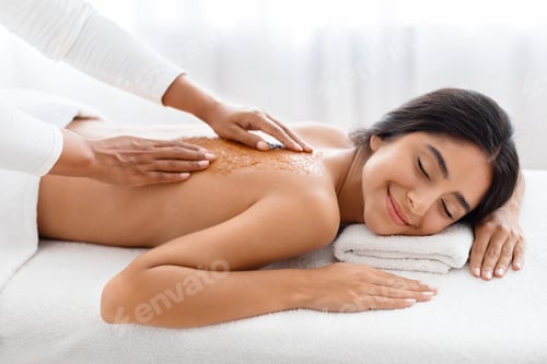 Preview: Relaxed young indian lady having skin scrubbing procedure at spa