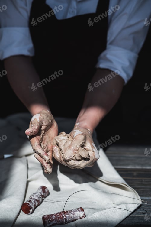 Preview: Woman's hands wet and dirty after working with clay in a pottery studio