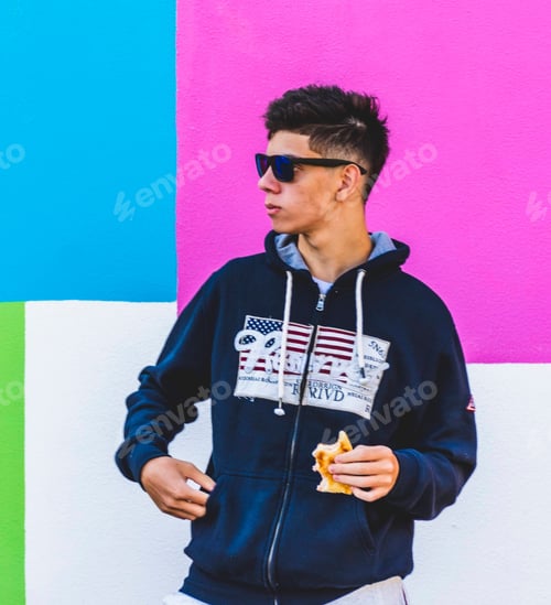 Preview: An italian teenager eating a sandwich in front of a colorful wall
