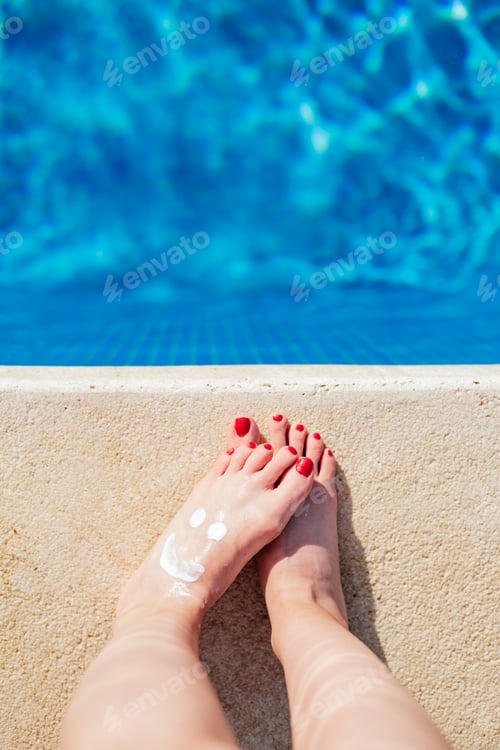 Preview: woman feet with a sunscreen smiley, view from above, copyspace, legs blurred, selective focus