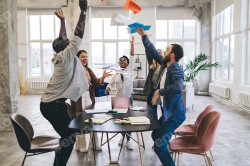 Preview: Group of multiracial colleagues celebrating success in spacious workspace