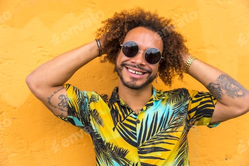 Preview: Attractive man with afro hair in summer summer in a palm tree shirt on a yellow background