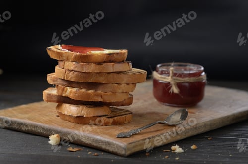 Preview: Toast bread with homemade strawberry jam and on rustic table with butter for breakfast or brunch.